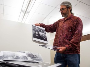 Andrew Miller, an Indigenous studies assistant professor at the First Nations University of Canada, displays historic photos in an office space at the university.