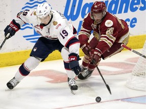 Regina Pats centre Jake Leschyshyn (19) and Acadie-Bathurst Titan forward Antoine Morand fight for the puck during the Memorial Cup in Regina on May 21, 2018.