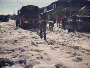 Moose Jaw residents help shovel hail from a street after school bus got stuck following a hail storm that hit the city on Tuesday night. Photo by Sean Schofer/Twitter)