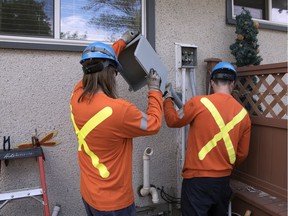 Alliance Energy employees Martin Doyle, left, and Mitch Harris add an expansion box under the power meter on this home in northwest Regina. The box adds approximately 1 metre of extra cable to allow for ground shifting.