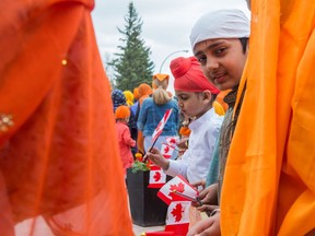 A child peeks out at the camera from behind a woman's dress prior to the start of the Sikh Day Parade, which began at the Sikh Society on Princess Drive and went to the Saskatchewan legislative building.