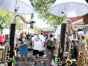 Brent Ghiglione, pictured laughing, maker of the instrument lamps and other household items, stands at his booth where he was selling his wares at the Cathedral Village Arts Festival Street Fair on 13th Avenue.