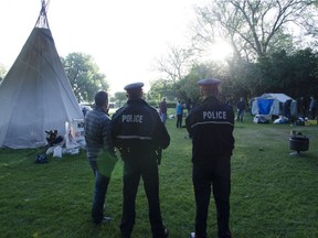 Police and a provincial employee look on as The Justice For Our Stolen Children Camp in front of the Legislative Building was taken down by force after 108 days. D.C. FRASER/Regina Leader-Post