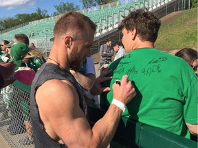 Saskatchewan Roughriders receiver Rob Bagg signs a fan's shirt during the team's annual Green and White Day in Saskatoon.