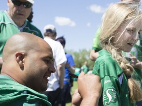 Riders defensive tackle Eddie Steele signs a jersey for Kate Richardson during a bar-b-que and autograph session in Humboldt recently.