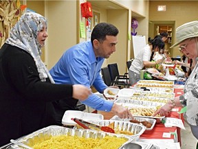 Abdulnaser Alkhalaf and his wife Hened sell traditional Syrian food to market-goer Connie Barrett at the Newcomers World Market hosted by the Westminster United Church.