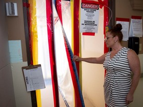 Anne Lindemann, communications consultant for the Saskatchewan Health Authority, holds open a zippered, plastic door at Pioneer Village where efforts are underway to rid the building of mould.