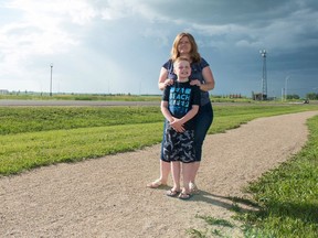 Shauna Poirier and her son Spencer stand on the gravel path that runs between Courtney Street and their house. The traffic light behind her in the distance is where Spencer will cross the street to walk to Plainsview School.