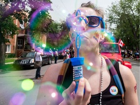 A participant blows bubbles at the camera while walking in the Pride parade on 13th Avenue.