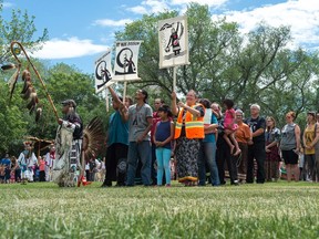 People stand together during the grand entry of the Trespassers Powwow at the Justice for our Stolen Children camp across from the Saskatchewan legislative building.