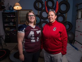 Amery Deren, left, a running back for the Regina Riot and her wife Bre Deren, team and equipment manager for the Riot, stand in the garage at their home. Amery is wearing a Regina Thunder jersey donated to the Riot after their team's jerseys were stolen.