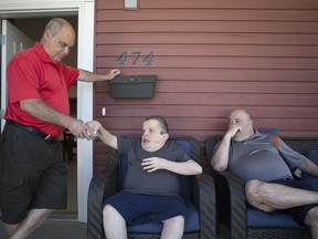 Jay Avivi (L) and Ari Avivi (R) hang out their brother David Avivi (C) outside during a visit at the Evergreen care home in Saskatoon on Sunday, July 15, 2018.