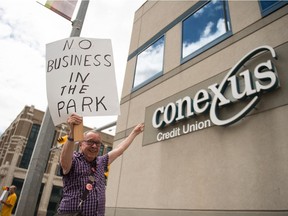 A protester holds a sign indicating his opposition to the plans of Conexus Credit Union to construct its new headquarters in Wascana Centre. He was waving his sign and pointing at the Credit Union's head office on Albert Street.