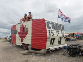 Jory Schwean (right) and Brandon McMullin sit atop a camper trailer to overlook the campground at the Country Thunder Saskatchewan music festival.