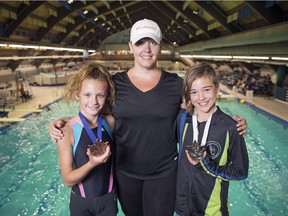 Presley Deck, left and Lila Stewart, right, stand with their diving coach Jana Klein at the Lawson Aquatic Centre in Regina. Each of the girls picked up a medal at the Speedo Junior Development Nationals diving competition in Toronto from July 6 to 8.