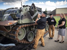 Lisa Pearce gets a tour of military vehicles from John Senior (C) and Scott Vanderveer after she donated her dad's military manuals to the Military Museum in Calgary on Friday, July 11, 2018.