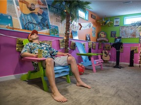 Stefan Hoffman, a diehard Jimmy Buffett fan or "Parrot Head", lounges in a chair giving his best relaxed pose in his Buffett-themed basement at his home in south Regina.