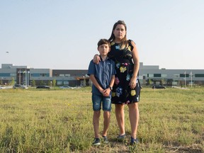 Erin Chard stands with her nine-year-old son Sam Chard in front of Ecole St. Elizabeth and Ecole Wascana Plains School. Bus routes differ between the two connected schools.