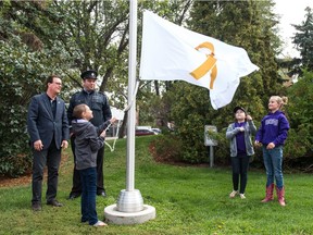 Regina mayor Michael Fougere, left, and a security guard look on as child volunteers assist at a flag raising event for International Childhood Cancer Awareness Month at Regina City Hall.