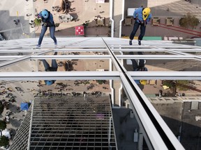 Madeline Pass  , left, and her father Chris Pass make their way down the side of Hill Tower 2 during The Easter Seals Drop Zone event in Regina.