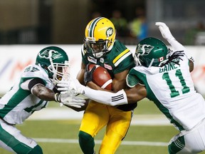 Edmonton Eskimos' Kenny Stafford (8) is tackled by Saskatchewan Roughriders' Marcus Thigpen (8) and Ed Gainey (11) during second half CFL action in Edmonton on Thursday, August 2, 2018.