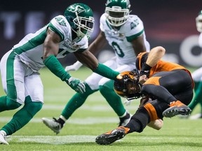 B.C. Lions' quarterback Travis Lulay, right, tumbles ahead to avoid a tackle from Saskatchewan Roughriders' Samuel Eguavoen, left, during the second half of a CFL football game in Vancouver, on Saturday August 25, 2018.