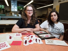 Elizabeth Elich, left, sits behind a collection of her artwork. Sitting next to her is Alejandra Cabrera of the Regina Public Library.