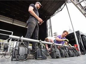 Volunteers Ryan Allen, left, Frank Nordstrom, centre and Justin Palmier assist in taking down the stage used for Regina Folk Fest in Victoria Park.