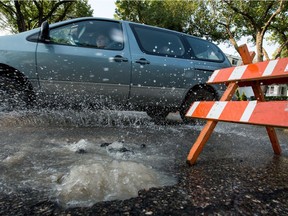 A motorist speeds by a water main break causing water to bubble up out of the road at the intersection of Victoria Avenue and Ottawa Street.