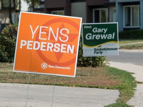 Campaign signs pertaining to the Regina NorthEast byelection stand on the edge of a street.