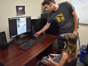Andrew Vierich, a software developer at the University of Guelph, looks on as Ruby Corbett learns how to safely cross streets using a virtual reality program Vierich helped design in this undated handout photo.