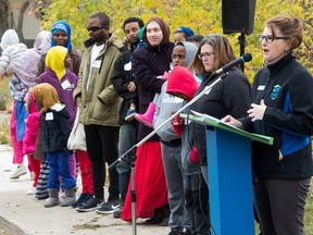Kelly Holmes-Binns, CEO of Regina's Habitat for Humanity, speaks at a sod-turning event to signal the beginning of 11 more homes at the site of the organization's Haultain Crossing project. In the crowd behind her stand some of the families who are slated to move into the homes.