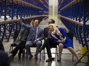 Ivonne Martinez, president of the Alberta Liquor Store Association, left, leans over as Alain Maisonneuve, president and CEO of the Alberta Gaming, Liquor and Cannabis Commission, takes a selfie with Finance Minister Joe Ceci and St. Albert Mayor Cathy Heron at the opening of a new liquor distribution centre on Wednesday, Sept. 19, 2018 in St Albert.