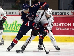 Aaron Hyman, left, of the Regina Pats battles for the puck with Ryan Peckford of the Moose Jaw Warriors on Sunday at the Brandt Centre.