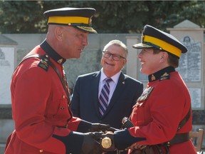 RCMP Commissioner Brenda Lucki receives the RCMP tip staff from former Commissioner Bob Paulson on the edge of the parade square at Depot Division in Regina. The act formalized the transfer of role from Paulson to Lucki. Standing behind them is federal minister of public safety Ralph Goodale.