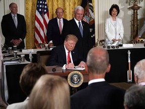 U.S. President Donald Trump signs an executive order as numerous officials look on during a meeting of the National Space Council at the East Room of the White House on June 18, 2018 in Washington, DC. Trump signed an executive order to establish the Space Force, an independent and co-equal military branch, as the sixth branch of the U.S. armed forces.