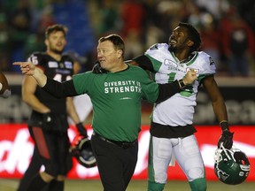 Saskatchewan Roughriders head coach Chris Jones holds back safety Mike Edem as he tries to calm a tense situation after Saturday's game against the Calgary Stampeders.