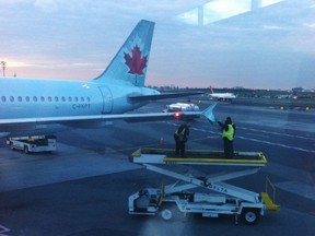 Runway crew members examine the wing tip of an Air Canada plane which arrived at LaGuardia Airport in New York on Monday, Oct. 22, 2018. An Air Canada flight that had just landed at New York's LaGuardia Airport late Monday afternoon was damaged as it sat on the taxiway by another passing plane. New York Port Authority spokesman Rudy King says the Air Canada jet was stationary on the taxiway when an American Airlines plane that was attempting to turn clipped its wing.