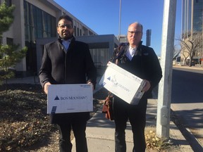 Westgate lawyers Sahil Shoor and Neil Abbott carry boxes carrying binders of documents and briefs of law out of the Court of Queen's Bench in Regina on Tuesday.