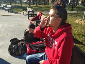 Tarek Svedahl takes a toke from a marijuana cigarette in Regina's Victoria Park as his friend Brandon Richards sits on the ground with various snack items.