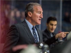 Moose Jaw Warriors head coach Tim Hunter watches his team during WHL exhibition play against the Regina Pats while associate coach Mark O'Leary offers instruction in the background.