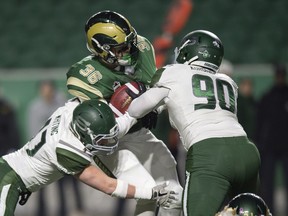 A pair of University of Saskatchewan Huskies defenders try to tackle University of Regina Rams running back Atlee Simon on Friday night at Mosaic Stadium.