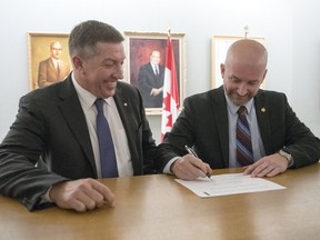 Respect Group Inc. co-founder Sheldon Kennedy, left, and Greg Tuer, assistant chair of the public service commission, sign a partnership in Regina to deliver Respect in the Workplace training for all Government of Saskatchewan employees.