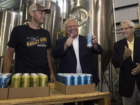 Ontario Premier Doug Ford and Vic Fedeli stack beer with Barley Days employee Kyle Baldwin before announcing the buck-a-beer plan at Barley Days brewery in Picton, Ont., on Tuesday Aug. 7, 2018.