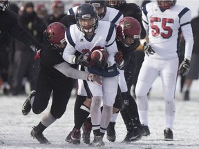 The Miller Marauders' Carter Sombach carries the ball, and some members of the Saskatoon Centennial Chargers, during Saturday's SHSAA 4A football final in Saskatoon. Miller won 43-0.