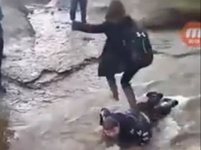 A shocking video posted to Facebook shows a 14-year-old Brett Corbett, lying face down in a rushing stream as another teen jumps onto him and then leapfrogs to the other side of the water to avoid getting wet. Around him are other students from Nova Scotia's Glace Bay High School -- watching, laughing, recording -- and one takes the opportunity to throw a rock at him. Credit: Brandon Jolie/Facebook