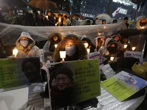 FILE - In this Dec. 30, 2015 file photo, college students hold portraits of the deceased former South Korean sex slaves who were forced to serve for the Japanese military in World War II, and lit candles during a rally against Japanese government in front of the Japanese Embassy in Seoul, South Korea. South Korea says it will dissolve a foundation funded by Japan to compensate South Korean women who were forced to work in Japan's World War II military brothels. Seoul's Ministry of Gender Equality and Family said Wednesday, Nov. 21, 2018,  it will take legal steps to dissolve the foundation.