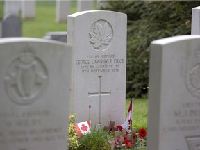 FILE - In this July 26, 2014, file photo, wooden crosses and Canadian flags adorn the grave of World War I Canadian soldier Pvt. George Lawrence Price, center, at the St. Symphorien Cemetery near Mons, Belgium. Price was the last Canadian soldier to die on the Western Front during the First World War.