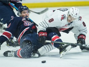 The Regina Pats' Logan Nijhoff (29) tumbles as he fights for the puck with the Moose Jaw Warriors Justin Almeida (8) during a WHL game at the Brandt Centre on Friday night.