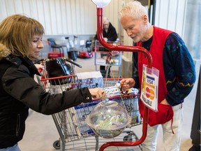 Tom Anderson mans the Salvation Army Christmas collection kettle while Velma Geddes puts in a donation at the exit of the Costco on Regina's east end.